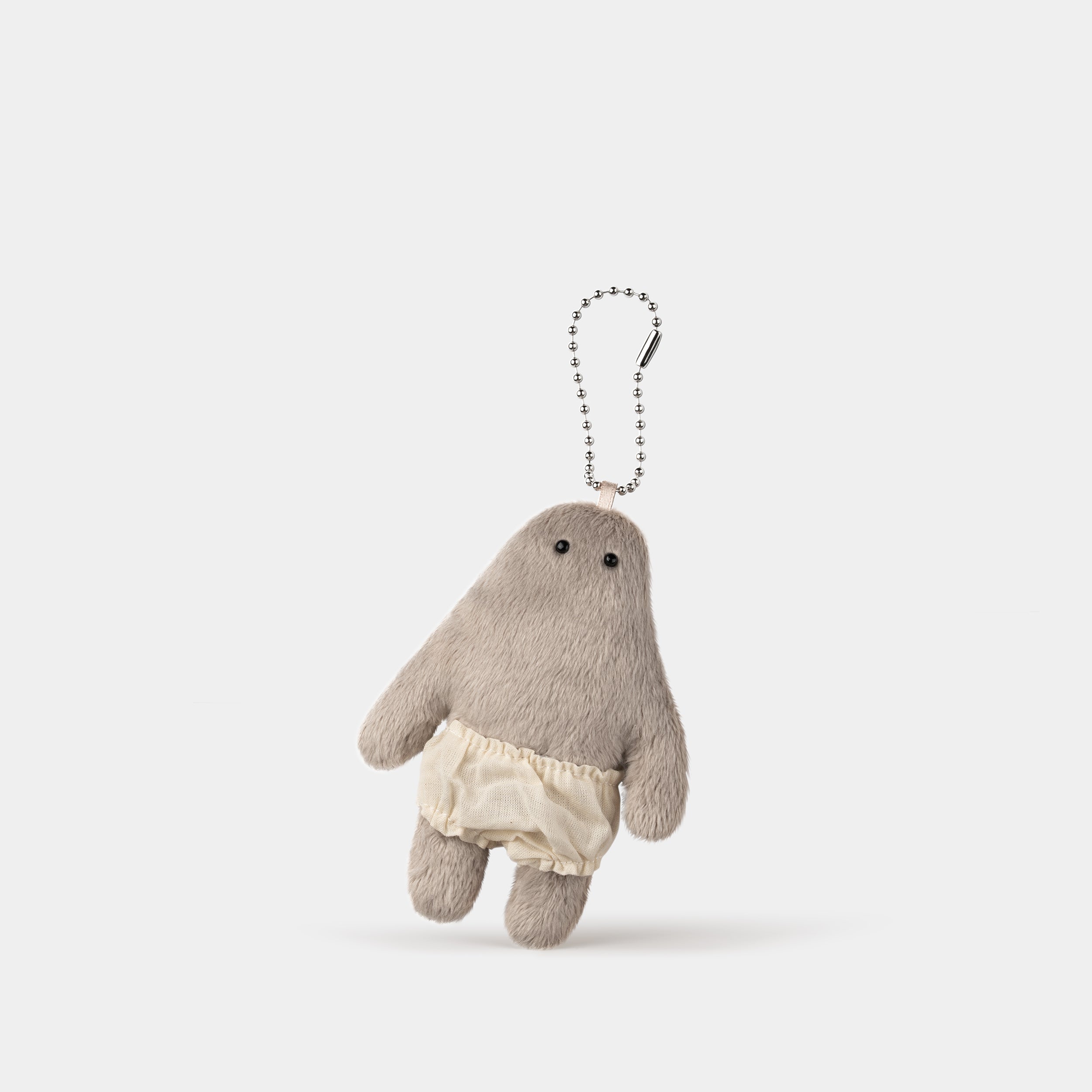 Opantsu-kun keychain appearing to levitate above a white surface, with one foot touching the surface and casting a shadow.